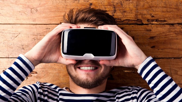 Man wearing virtual reality goggles. Studio shot, wooden background; Shutterstock ID 385433683; PO: JLL Brand Refresh batch 3; project code: JLL Brand Refresh; department code: JLL Marketing; bill to: R Thrift