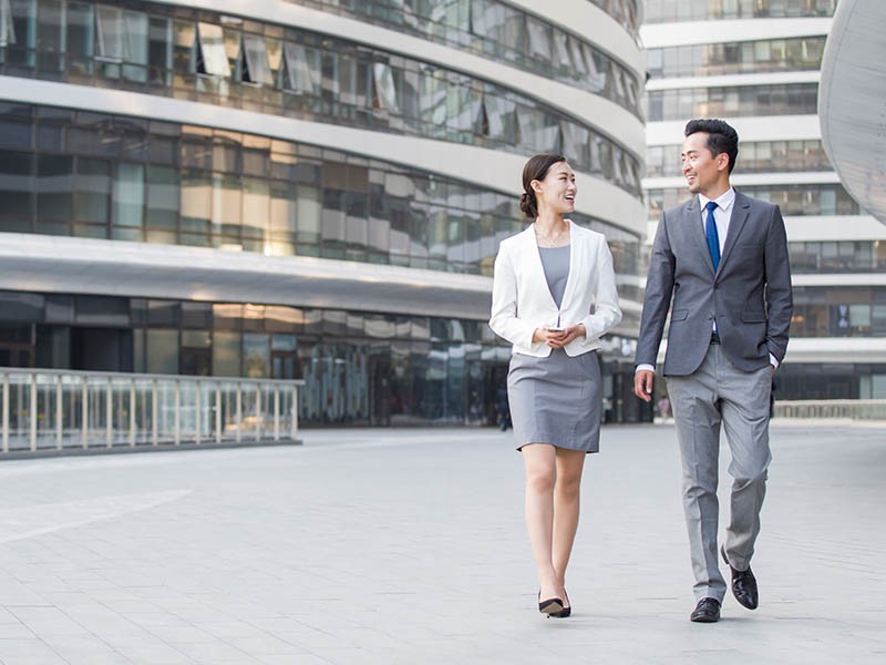 Two business professionals walking outside the office building and discussing the new project