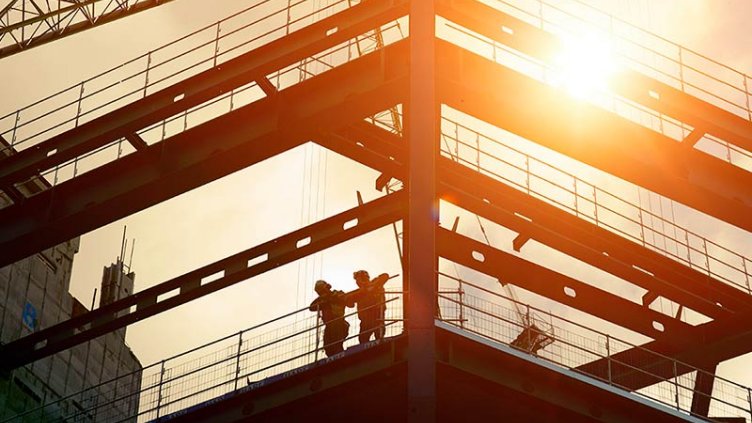 Construction workers silhouetted against the sun