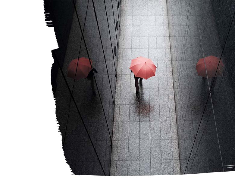 Rear view of man walking on city street with red umbrella