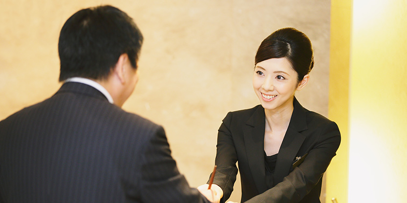 Smiling front-desk lady serving a hotel guest