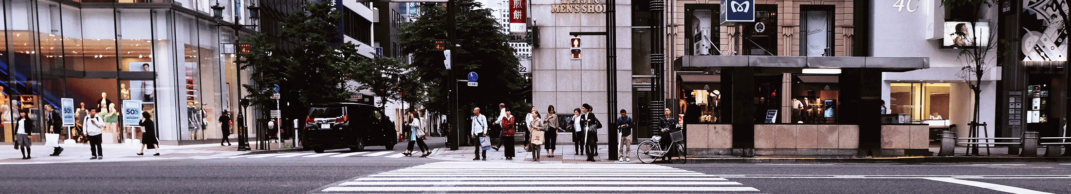 Group of people crossing the road on pedestrian crossing outside the shopping mall