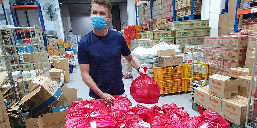 A man packing the goods and items in the packets for the charity during Covid