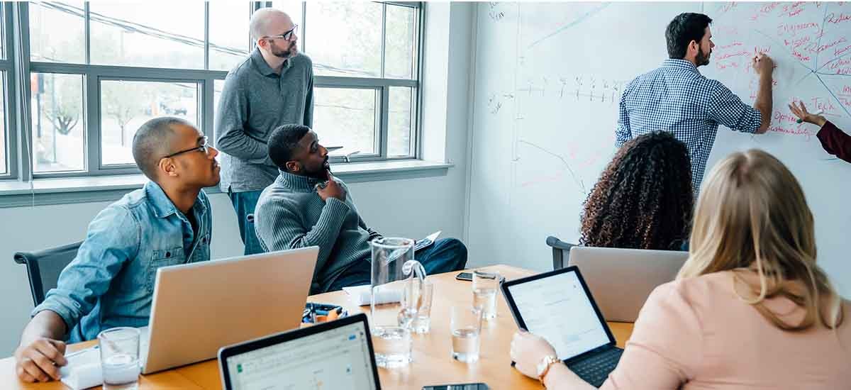 Employees having meeting and discussing the things by writing on the whiteboard inside a meeting room